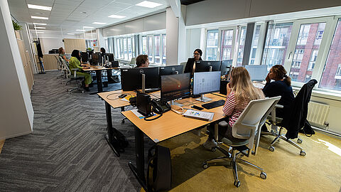 meerdere personen achter bureau met laptop